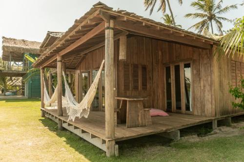 a wooden shack with a hammock in a yard at Casa na Lagoa in Paracuru