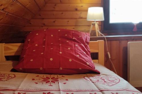 uma almofada vermelha sentada em cima de uma cama em LA RUSTIQUE DU BOUT DU LAC em Chambon-sur-Lac
