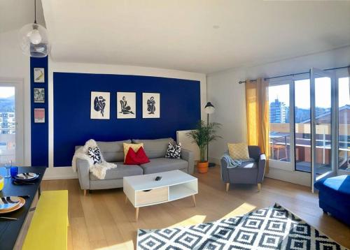 a living room with a couch and a blue wall at Charmant Appartement Pop - Arty in Thonon-les-Bains