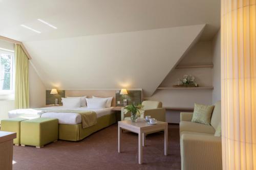 a hotel room with a bed and a couch and chairs at Kur und Wellnesshaus Spreebalance, The Originals Relais (Relais du Silence) in Burg