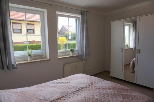 a bedroom with a bed and two windows at Merikoti in Glowe