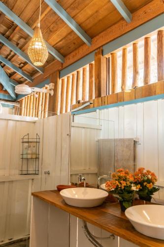 a bathroom with two sinks and flowers on a counter at Casa na Lagoa in Paracuru