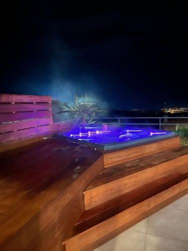 - une piscine avec des lumières violettes sur une terrasse la nuit dans l'établissement IsulaRossaBellaVista-GrandPenthouse, à LʼÎle-Rousse