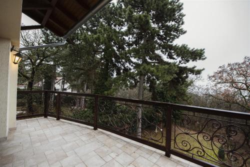 a balcony with a black fence and trees at Hilltop Wellness Villa-big garden, sauna, hot tube in Pécs