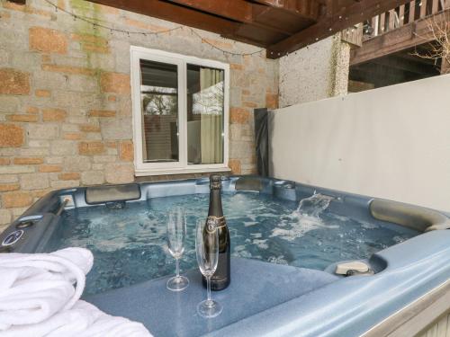 a hot tub with a bottle of champagne and two wine glasses at Valley Lodge 48 in Callington