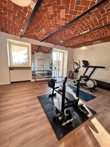 a gym with a brick wall and two tread machines at Dimora Roè in Monticello d'Alba