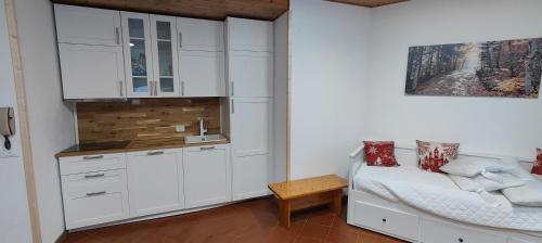 a kitchen with white cabinets and a bed and a table at La casetta di Diego in Abetone