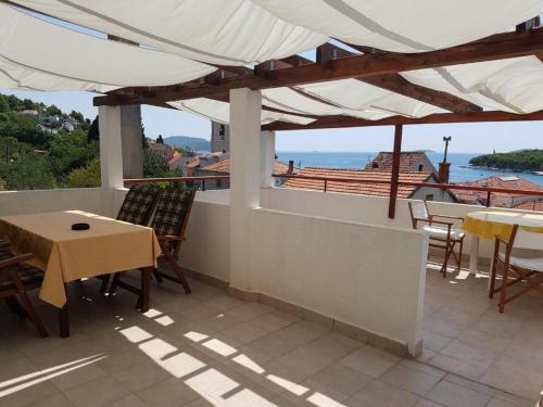 een balkon met een tafel en stoelen en uitzicht op de oceaan bij Apartment Luca in Prvić Luka