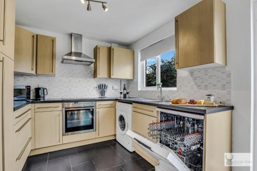 a kitchen with wooden cabinets and a dishwasher at Spacious Whitwick Stay 3-Story House in Whitwick