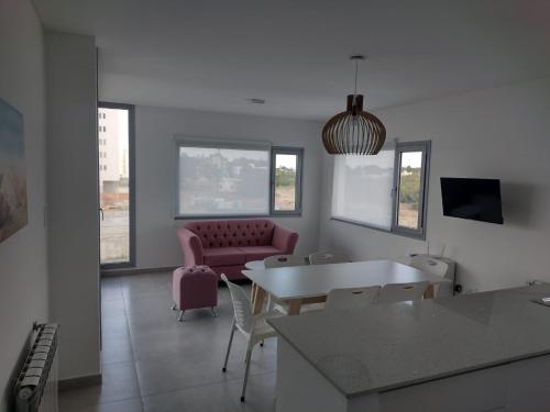 Una sala de estar con una mesa y un sofá rosa. en Al Mar - Torres del Este, en Monte Hermoso
