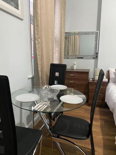 007- S1premium location studio apartment central London في لندن: غرفة طعام مع طاولة وكراسي زجاجية