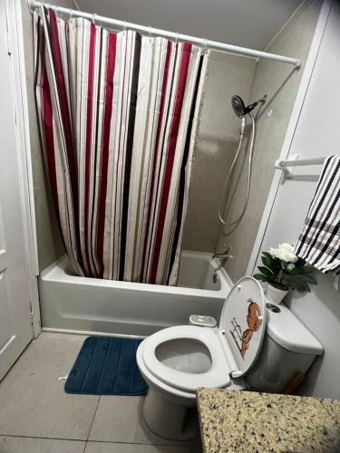 a bathroom with a toilet with a shower curtain at Cozy private room in Brampton