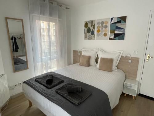 a white bedroom with a large bed with towels on it at Aix Homes "Les Allées Provençales" in Aix-en-Provence