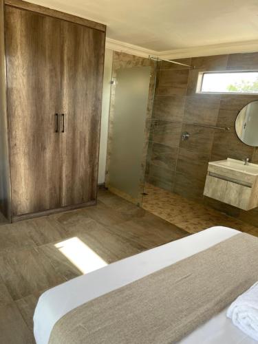 baño con ducha, cama y lavamanos en Bluewave Farm Villa, en Louis Trichardt