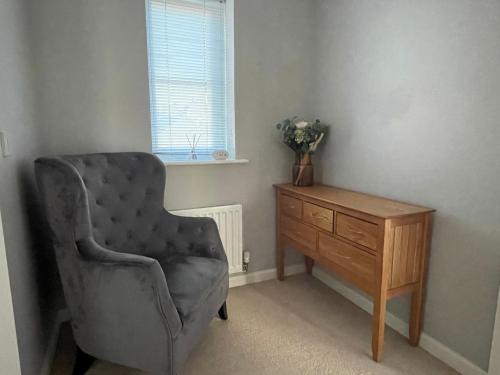 a room with a chair and a wooden dresser at Detached family house with private garden. in Arlesey