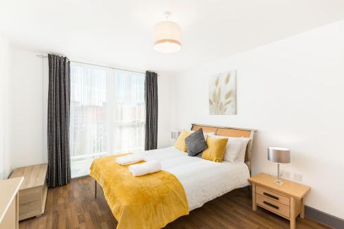 ein Schlafzimmer mit einem Bett mit einer gelben Decke darauf in der Unterkunft Comfort Living Properties - Deluxe Apt, Birmingham City Centre in Birmingham