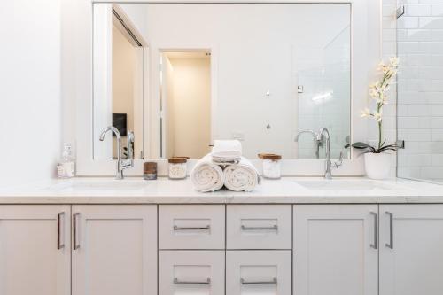 Baño blanco con 2 lavabos y espejo en Stylish & Perfectly Located Luxury 2-Bed Townhome, en Dallas