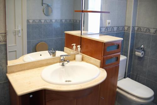 a bathroom with a sink and a toilet and a mirror at Villa La Perla de Sonabia in Oriñón