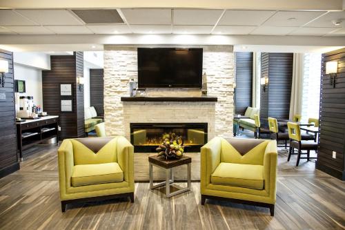 a lobby with two yellow chairs and a fireplace at Kitchener Inn & Suites in Kitchener