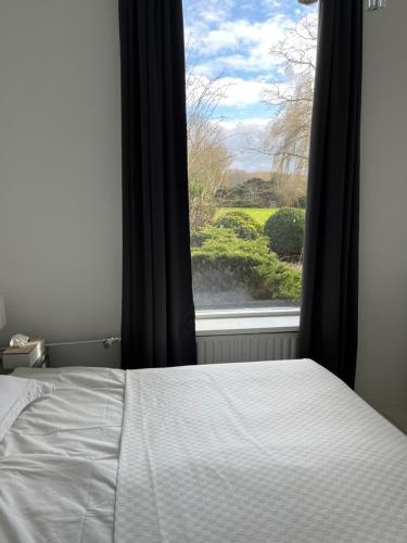 a bedroom with a bed and a window with a view at domaine de la bergerie in Zuid-Beijerland