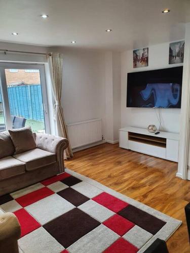 a living room with a couch and a flat screen tv at Spacious and Tastefully Decorated Town House In Lakeside West Thurrock Grays in West Thurrock