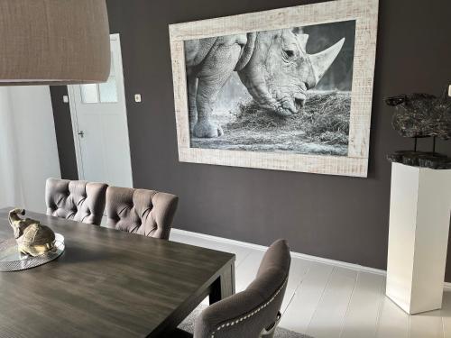 a dining room with a table and a picture of a rhino at domaine de la bergerie in Zuid-Beijerland