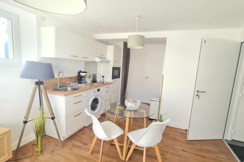 een keuken met een glazen tafel en witte stoelen bij Le Jaures 2 - T2 - RDC in Hennebont