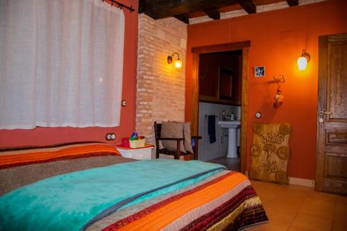 a bedroom with orange walls and a bed and a bathroom at CASA RURAL EL RONDILLO in Navaconcejo