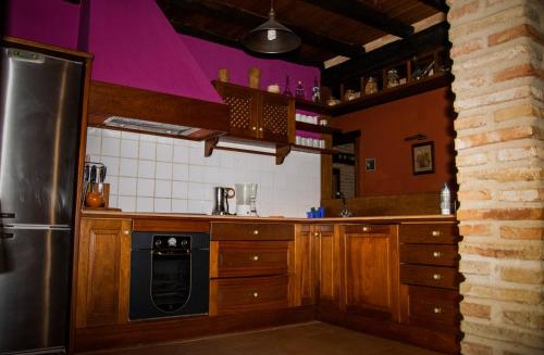 a kitchen with wooden cabinets and a stainless steel refrigerator at CASA RURAL EL RONDILLO in Navaconcejo