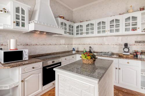 a white kitchen with white cabinets and a bowl of fruit on the counter at Home Away From Home in Caniçal