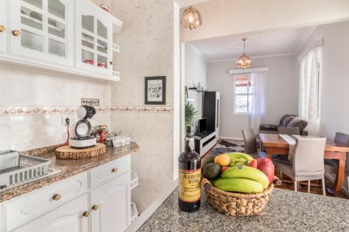 a kitchen with a basket of fruit and a bottle of wine at Home Away From Home in Caniçal