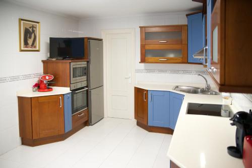 a kitchen with blue cabinets and a white floor at Villa La Perla de Sonabia in Oriñón