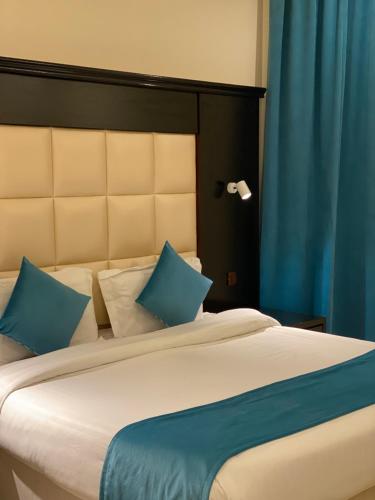 a bedroom with a large bed with blue pillows at Samaa Eva Resort in Abha