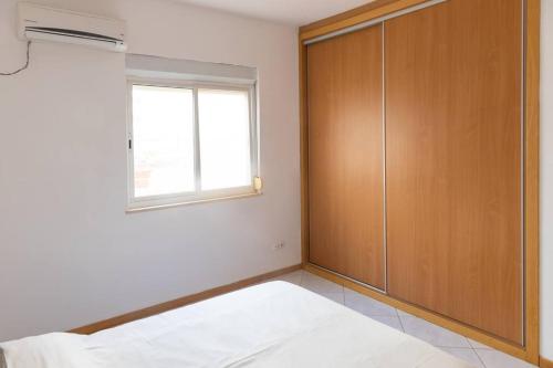 a bedroom with a wooden closet and a window at 3 bedroom apt, Exterior POOL , Cidadela - LCGR in Praia