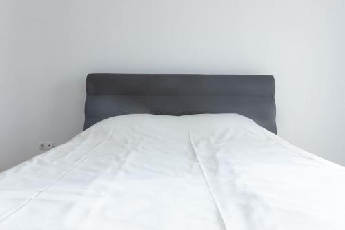 a bed with white sheets and a black headboard at 3 bedroom apt, Exterior POOL , Cidadela - LCGR in Praia