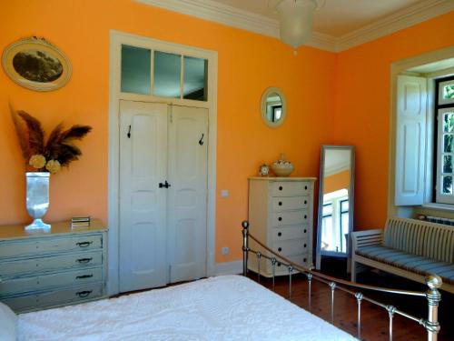 1 dormitorio con paredes de color naranja, 1 cama y espejo en B&B Quarto Rosa Estilo Romântico 