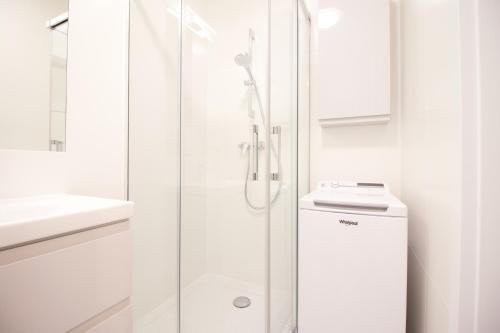baño blanco con ducha y lavamanos en Hygge Malta - NOWY apartament, en Poznan