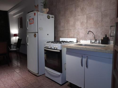 La cocina está equipada con nevera, fogones y fregadero. en Dúplex La Nona en Salta