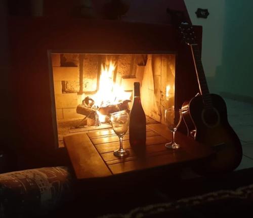 a fireplace with two wine glasses and a guitar at CASA DE CAMPO DOS SONHOS in São José dos Campos