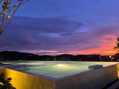 una piscina por la noche con puesta de sol en Laguna SkyPark 1609 вид на гольф поле 2 спальни 2 санузла 6 этаж три 25 метровых бассейна на крыше 500 М бит интернет en Bang Tao Beach