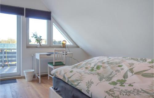 a bedroom with a bed and a desk and windows at 2 Bedroom Awesome Apartment In Loxstedt in Loxstedt