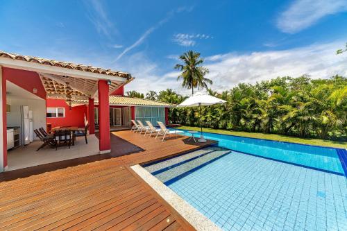 a house with a wooden deck and a swimming pool at Quintas de Sauípe - Casa D13 in Costa do Sauipe