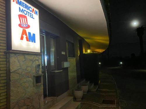 a sign on the side of a building at night at American Motel in Cisterna di Latina