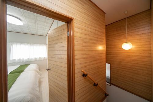 1 dormitorio con 1 cama y pared de madera en Yokkaichi City - House - Vacation STAY 68977v, en Nishi-hino