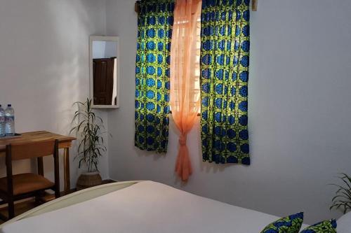 a bedroom with curtains and a table and a bed at Maison fleurie Ouidah in Ouidah