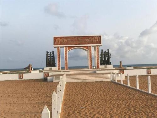 a monument on the beach near the ocean at Maison fleurie Ouidah in Ouidah