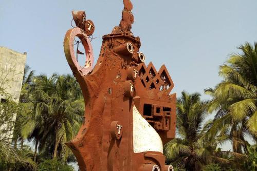 a statue of an elephant with palm trees in the background at Maison fleurie Ouidah in Ouidah