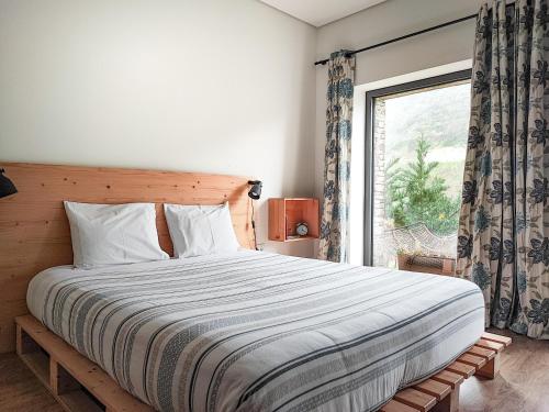 a bedroom with a large bed with a window at Dois Lagares House in Pinhão