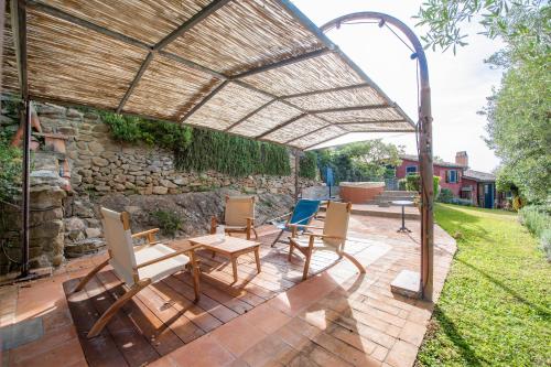 a wooden pergola with chairs and tables on a patio at PODERE TORRICELLE 69B Pancole Gr, seaview infinity pool, jacuzzi, sauna, exclusive villa with 2 bedrooms for 4 - If you total 5 or 6 people there is an independent suite in main villa with private ensuite bathroom, kitchenette and garden dining area in Pancole