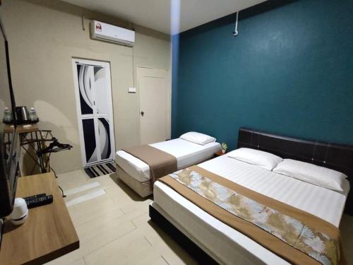 a bedroom with two beds and a blue wall at TC Maya Abaya Hotel in Kuantan